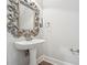 Powder room featuring a white pedestal sink, ornate mirror, and classic base molding at 10686 Austen Bnd, Alpharetta, GA 30022
