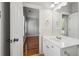 Bathroom featuring white vanity with sink and mirror, open doorway to bedroom with hardwood floors at 10686 Austen Bnd, Alpharetta, GA 30022