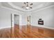 Main bedroom with hardwood floors, tray ceilings, a fireplace, and ensuite bath access at 10686 Austen Bnd, Alpharetta, GA 30022