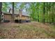 Backyard view showcases a deck, wood exterior, and mature trees in a lush setting at 6693 Doublegate Ln, Rex, GA 30273