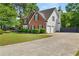 View of the home showing the two-car garage, well manicured lawn, and mature trees at 990 Lilac Arbor Rd, Dacula, GA 30019