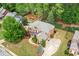 Aerial view of a brick home featuring manicured lawns, lush landscaping, and an attached three-car garage at 893 Paces Farm Sw Trl, Marietta, GA 30064