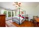 Bright bedroom featuring a four-poster bed, hardwood floors, and large windows at 3545 River Summit Trl, Duluth, GA 30097