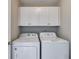 A well-lit laundry area featuring white front-load washer and dryer with overhead cabinets at 36 Evergreen Way, Dallas, GA 30157
