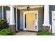 Close-up of the yellow front door with glass sidelights, columns, and manicured shrubs at 6859 Winding Wade Trl, Austell, GA 30168