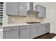 Shows the gray cabinetry, white countertops, tiled backsplash and stainless steel range in this modern kitchen at 6859 Winding Wade Trl, Austell, GA 30168