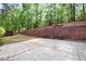 Backyard patio with wooden retaining wall and landscaped hillside in a wooded neighborhood at 6859 Winding Wade Trl, Austell, GA 30168