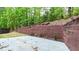 Backyard patio with wooden retaining wall and landscaped hillside in a wooded neighborhood at 6859 Winding Wade Trl, Austell, GA 30168