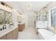 Luxurious bathroom featuring marble tile, a soaking tub, and double vanities at 1670 Bookhout Dr, Cumming, GA 30041