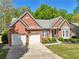 Charming red brick home with a two-car garage, manicured lawn, and lovely landscaping at 1670 Bookhout Dr, Cumming, GA 30041