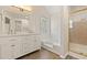 Bathroom with double sinks, white cabinetry, shower with tile walls, tub, and window at 2317 Rocksram Ct, Buford, GA 30519