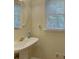 Charming half bath featuring a pedestal sink, round mirror, and window with natural light at 1871 Birch Briar Bnd, Lawrenceville, GA 30043