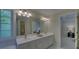 Bright bathroom featuring double sinks, large mirror, vanity with cabinetry, tile flooring, and doorway to bedroom at 1871 Birch Briar Bnd, Lawrenceville, GA 30043
