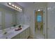 Bright bathroom featuring double sinks, vanity with cabinetry, tile flooring, large mirror, and doorway to toilet room at 1871 Birch Briar Bnd, Lawrenceville, GA 30043