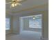 Spacious bedroom with a tray ceiling, ceiling fan, neutral carpet, and doorway to an adjoining room at 1871 Birch Briar Bnd, Lawrenceville, GA 30043
