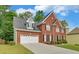 Beautiful two-story red brick home with manicured lawn and a two car garage on a sunny day at 1871 Birch Briar Bnd, Lawrenceville, GA 30043