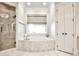 Elegant bathroom featuring a soaking tub, glass-enclosed shower, and double doors at 4140 Hillside Nw Pl, Atlanta, GA 30342