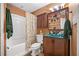 Cozy bathroom features a shower-tub combo, stylish vanity, mirror, and decorative cabinet at 5525 Tallantworth Trl, Cumming, GA 30040