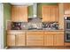Kitchen features wood cabinets, tile backsplash, stainless hood vent, and a gas cooktop at 5525 Tallantworth Trl, Cumming, GA 30040