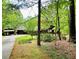 Scenic view of a home with driveway and open shed through the trees, highlighting its private setting at 880 Havenridge Dr, Conyers, GA 30094