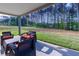 A covered patio has a cozy seating area with a lovely view of the green backyard and mature trees at 61 N Village Cir, Rydal, GA 30171