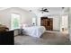 Bright bedroom with carpet, ceiling fan, and large windows providing ample natural light and view to bathroom at 680 Ruxbury Ct, Suwanee, GA 30024