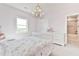 Bright bedroom showcasing a decorative chandelier, a white dresser, and an adjacent bathroom at 5315 Hendrix Rd, Cumming, GA 30040