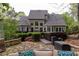 Back of home features large deck, a patio with hot tub, stone wall, and lush landscaping at 176 Nightwind Trce, Acworth, GA 30101