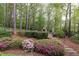 Tranquil backyard with a stone fireplace, lush landscaping, and a wooded backdrop at 176 Nightwind Trce, Acworth, GA 30101