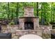 Cozy outdoor stone fireplace surrounded by lush greenery, perfect for enjoying cool evenings at 176 Nightwind Trce, Acworth, GA 30101