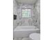 Bathroom features a white bathtub with marble-style tile surround, window, and niche for toiletries at 6454 Boca Grande Blvd, Forest Park, GA 30297