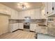 A bright kitchen with white cabinets, granite countertops, and stainless steel appliances offers modern appeal at 6454 Boca Grande Blvd, Forest Park, GA 30297