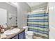 Bright bathroom featuring a single sink vanity with blue cabinets and a shower with a striped curtain at 898 Allene Sw Ave, Atlanta, GA 30310