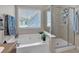 Bright bathroom featuring separate tub and shower with neutral tile and a large window at 905 Fox Croft Pl, Canton, GA 30114