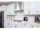 Contemporary kitchen featuring white cabinets and a modern range hood over a flat cooktop at 1771 Jordan Brook Dr, Lawrenceville, GA 30043