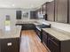 Modern kitchen featuring granite countertops, stainless steel appliances, dark cabinets, and stylish hardwood floors at 4428 Belcamp Rd, Fairburn, GA 30213