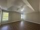 Spacious bedroom featuring a tray ceiling, ceiling fan, wood-look flooring and two windows at 3835 Portico Run Dr, Buford, GA 30519