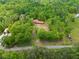 Aerial view of home featuring lush surrounding trees, a visible red roof and various outbuildings enhance this stunning property at 751 Upper Burris Rd, Canton, GA 30114
