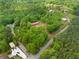 Picturesque aerial view of the property nestled among lush green trees, showcasing the home with its red roof, pond and open land at 751 Upper Burris Rd, Canton, GA 30114