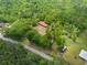 Aerial view captures the home with a red roof, set amidst lush greenery, complemented by a long driveway and surrounding trees at 751 Upper Burris Rd, Canton, GA 30114
