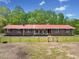 Stunning one-story brick home with a metal roof, white columns, dark shutters, green lawn, and a split rail fence surrounding the property at 751 Upper Burris Rd, Canton, GA 30114