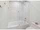 All-white bathroom featuring a shower and tub combination with glass door, tile surround and shell decor at 11540 Northgate Way, Roswell, GA 30075