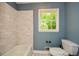 Bathroom featuring a tub with tile surround, a toilet and window at 2840 Wendy Ln, Marietta, GA 30062