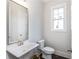 Charming powder room with a pedestal sink, framed mirror, and natural light from the window at 1417 Coretta Scott Bnd, Atlanta, GA 30318