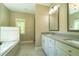 Bright bathroom featuring double sinks, white cabinets, framed mirrors and relaxing tub at 2025 Goldmine Dr, Cumming, GA 30040