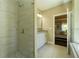 Modern bathroom with tiled shower and glass door, next to vanity with a bedroom doorway at 2025 Goldmine Dr, Cumming, GA 30040