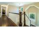 Upstairs hallway with hardwood floors, white railing and dark wood banister and window at 2025 Goldmine Dr, Cumming, GA 30040