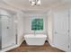 Bright bathroom featuring a large tub, glass shower, and a large window with a view at 1400 Squire Ln, Cumming, GA 30041