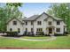 Stunning two-story home featuring a lush front lawn, manicured landscaping, and a charming stone and stucco facade at 1400 Squire Ln, Cumming, GA 30041