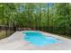 Kidney-shaped in-ground swimming pool surrounded by concrete pool deck and black metal safety fence at 1400 Squire Ln, Cumming, GA 30041